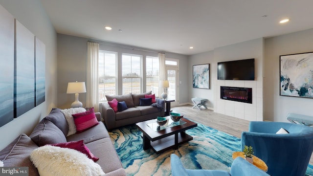 living room with a tiled fireplace and hardwood / wood-style floors