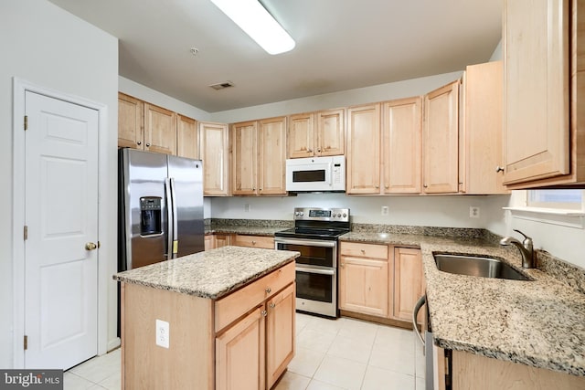 kitchen featuring a kitchen island, light brown cabinetry, sink, and appliances with stainless steel finishes