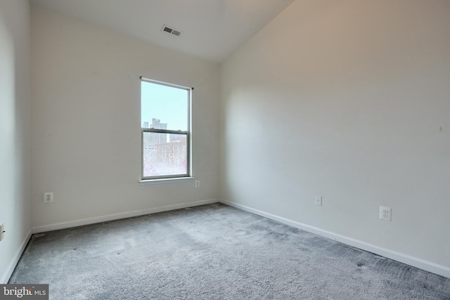 carpeted empty room featuring vaulted ceiling