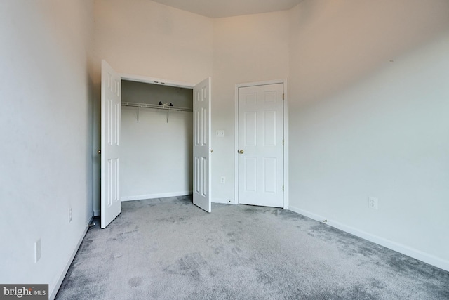 unfurnished bedroom featuring a towering ceiling, light colored carpet, and a closet