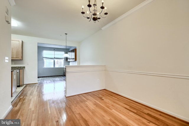 unfurnished dining area featuring light wood-type flooring, ornamental molding, and an inviting chandelier