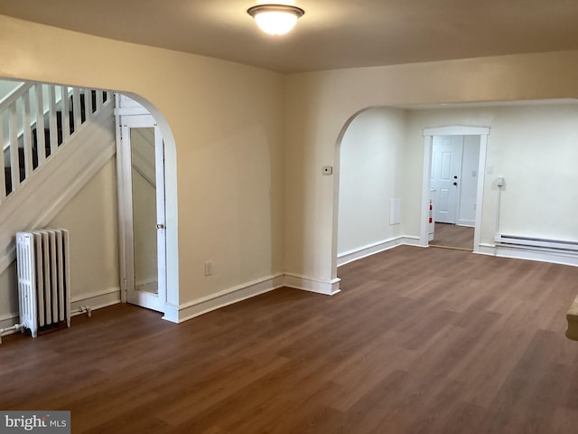 spare room featuring baseboard heating, radiator heating unit, and dark wood-type flooring