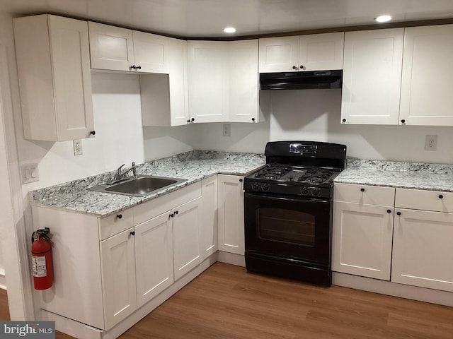 kitchen featuring white cabinets, gas stove, light wood-type flooring, and sink