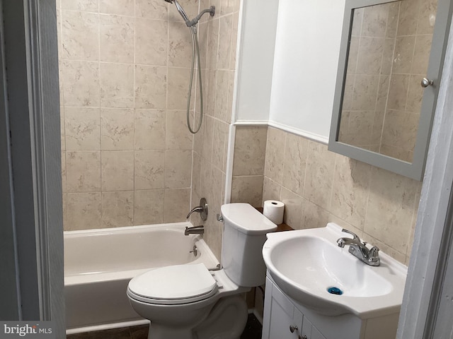 full bathroom with tiled shower / bath, vanity, tile walls, and toilet