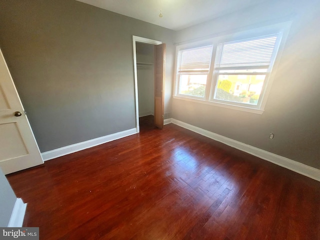 unfurnished bedroom with a closet and dark wood-type flooring