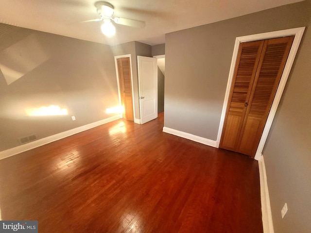 unfurnished bedroom with ceiling fan and dark wood-type flooring