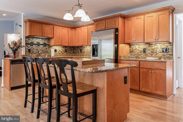 kitchen with stone countertops, ornamental molding, appliances with stainless steel finishes, and a chandelier