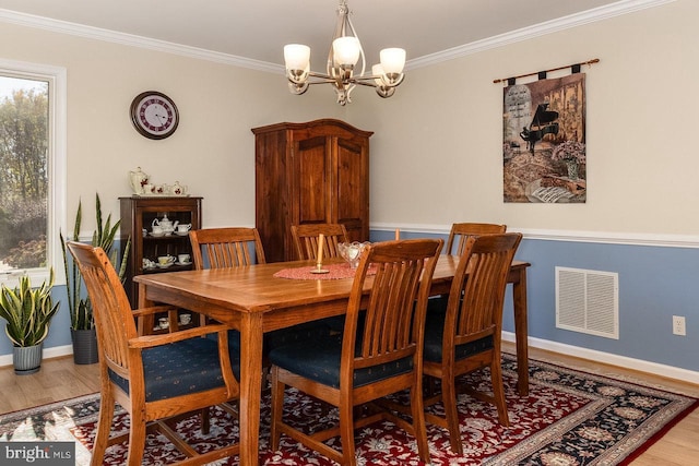 dining room with wood-type flooring, crown molding, and a notable chandelier