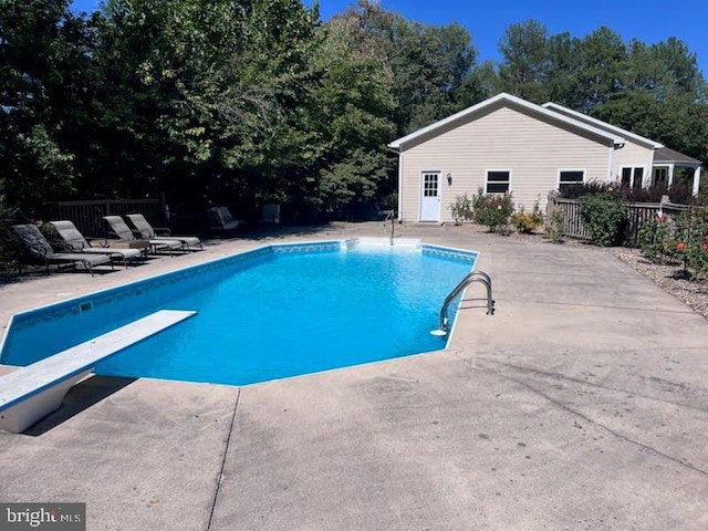 view of swimming pool with a diving board and a patio