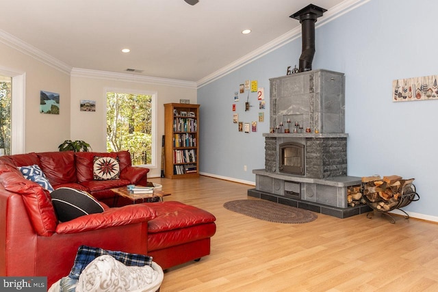 living room featuring a wood stove, crown molding, and wood-type flooring