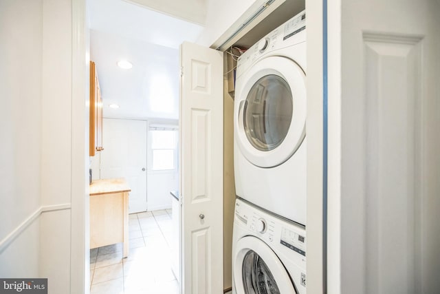 laundry area with light tile patterned floors and stacked washer and clothes dryer