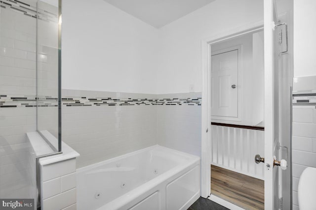 bathroom with a bath, wood-type flooring, and tile walls