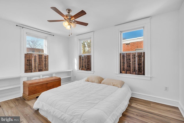 bedroom with ceiling fan, light wood-type flooring, and multiple windows