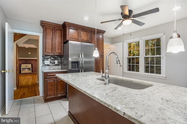 kitchen featuring ceiling fan, sink, stainless steel refrigerator with ice dispenser, decorative light fixtures, and light tile patterned floors