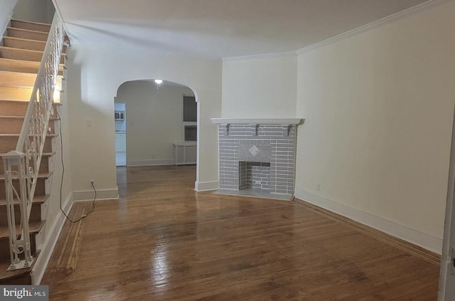 unfurnished living room featuring dark hardwood / wood-style floors, a brick fireplace, and ornamental molding