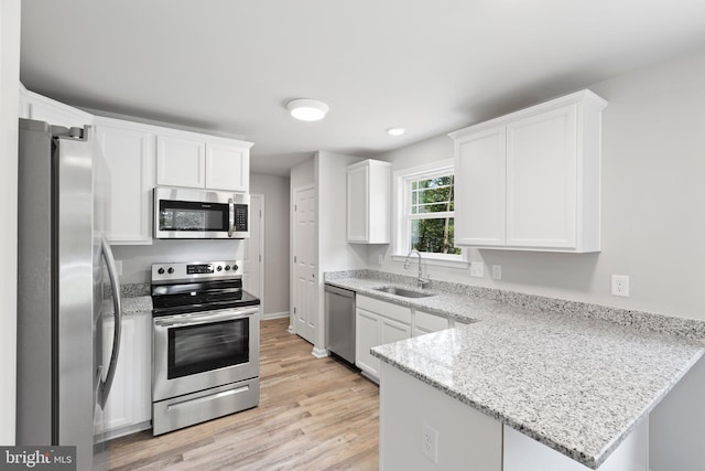 kitchen featuring light stone countertops, white cabinets, light wood-type flooring, and appliances with stainless steel finishes