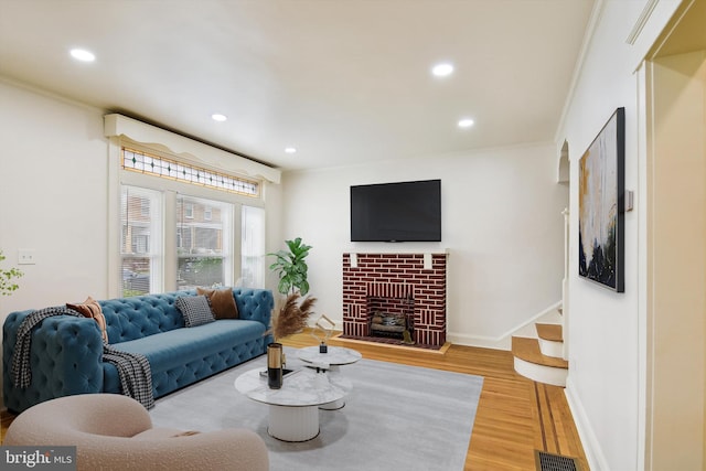 living room featuring a fireplace, hardwood / wood-style flooring, and crown molding