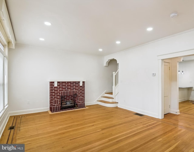 unfurnished living room with crown molding, a fireplace, and wood-type flooring