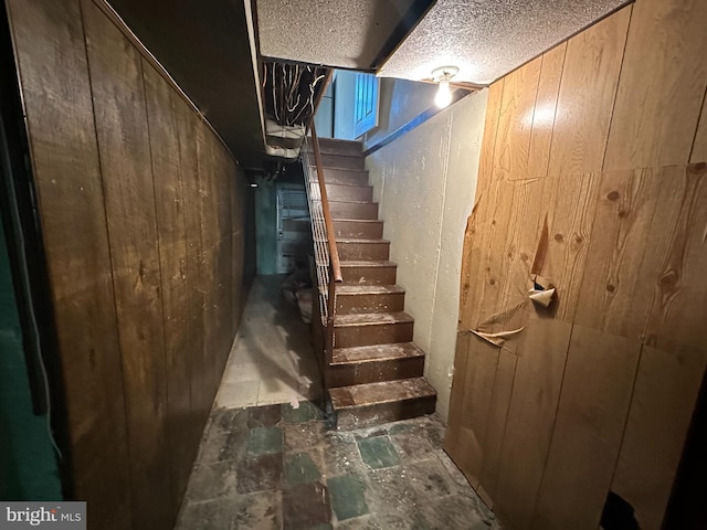 basement featuring a textured ceiling and wooden walls