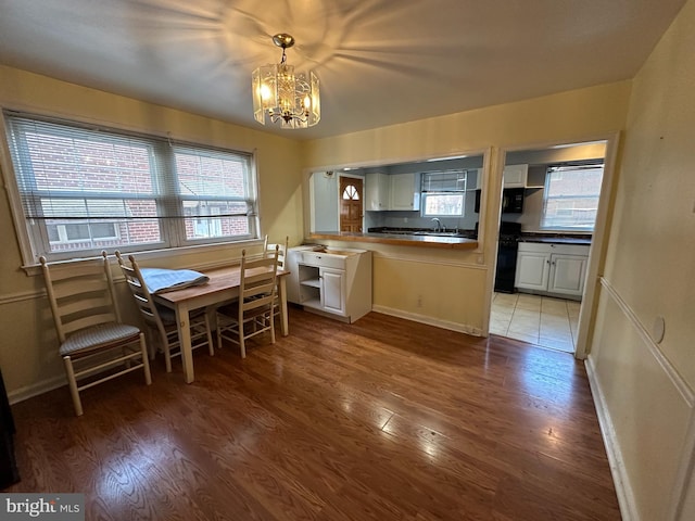 kitchen with white cabinetry, sink, an inviting chandelier, decorative light fixtures, and light wood-type flooring