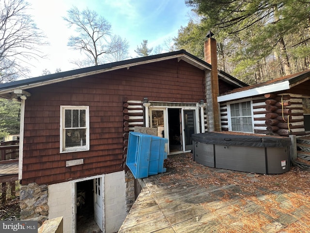 rear view of property with a hot tub and a wooden deck