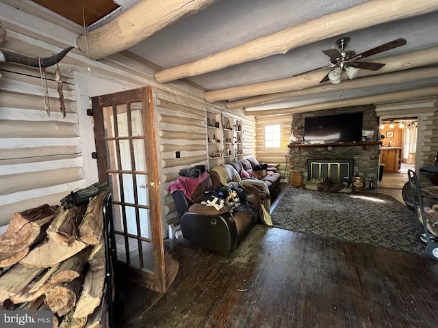 living room featuring hardwood / wood-style flooring, ceiling fan, a fireplace, rustic walls, and beam ceiling