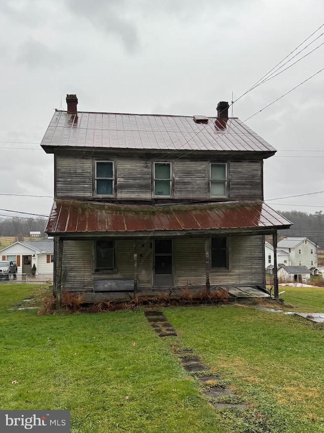 rear view of property featuring a lawn and a porch