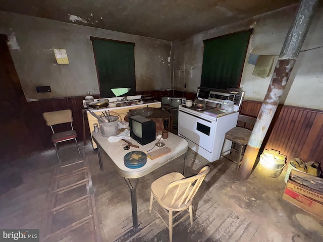 kitchen featuring white stove and wood walls