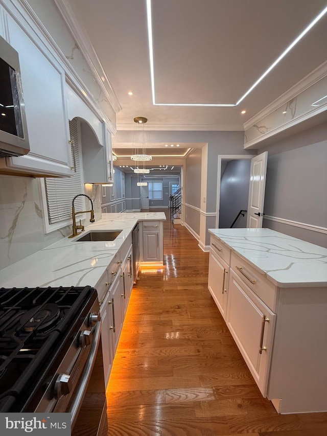 kitchen with pendant lighting, sink, decorative backsplash, light stone countertops, and light hardwood / wood-style floors