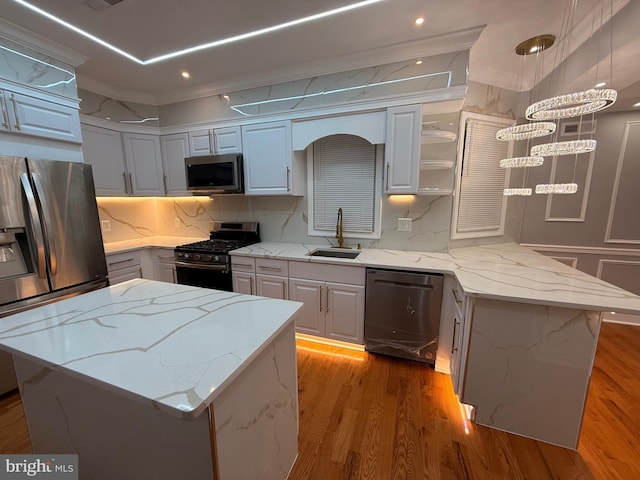 kitchen featuring light stone counters, stainless steel appliances, sink, white cabinets, and a kitchen island