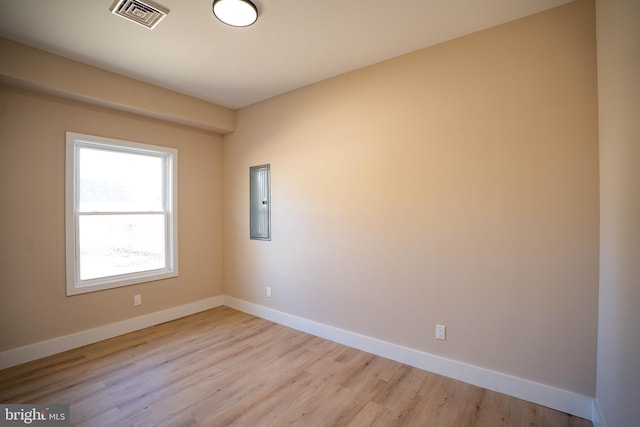 unfurnished room featuring electric panel and light hardwood / wood-style floors