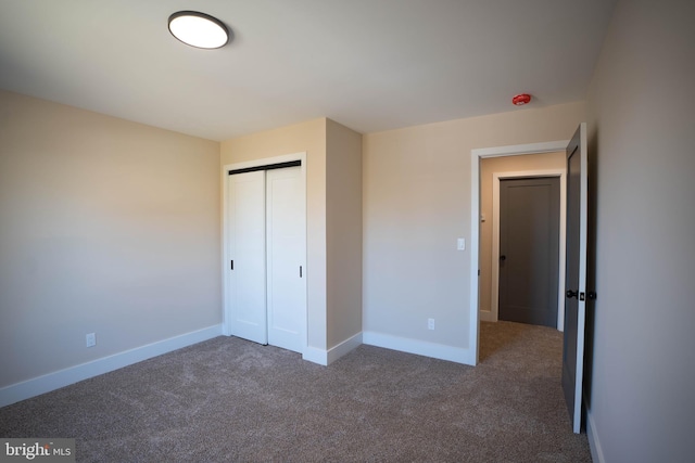 unfurnished bedroom featuring dark colored carpet and a closet