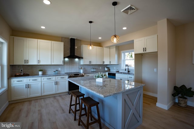 kitchen with a center island, white cabinets, electric stove, sink, and wall chimney exhaust hood