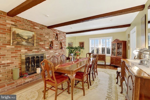 dining room with light wood-type flooring, a fireplace, and beam ceiling