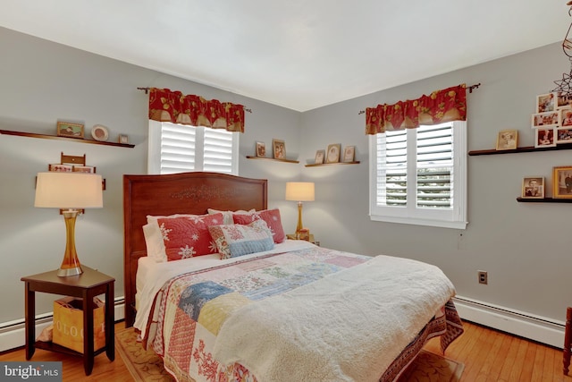 bedroom featuring a baseboard heating unit, multiple windows, and wood finished floors