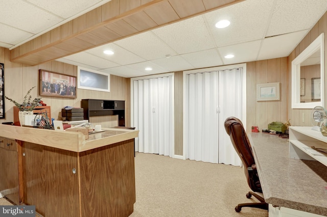 office space with recessed lighting, light carpet, a paneled ceiling, and wooden walls