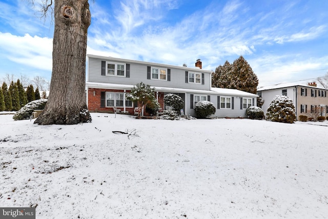 snow covered house with a chimney and brick siding