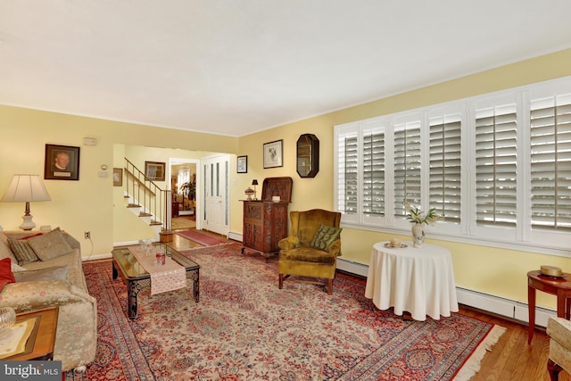 living room with baseboards, stairway, baseboard heating, and wood finished floors