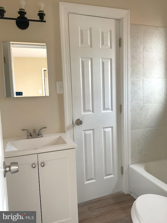 bathroom with hardwood / wood-style floors, vanity, and toilet