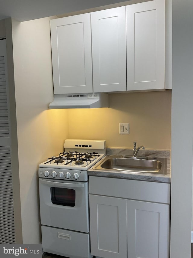 kitchen featuring white gas range, white cabinetry, and sink