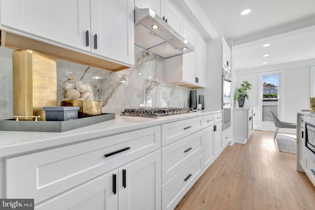 kitchen featuring white cabinets, light hardwood / wood-style floors, and extractor fan