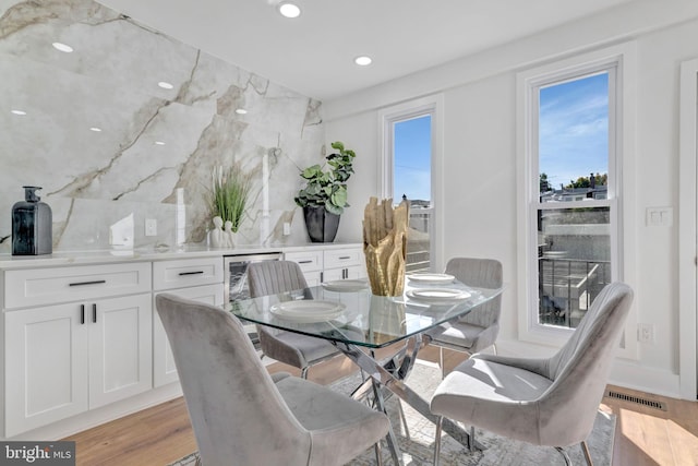 dining space with light hardwood / wood-style floors and beverage cooler