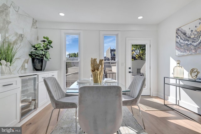 dining space featuring bar area, wine cooler, and light hardwood / wood-style flooring