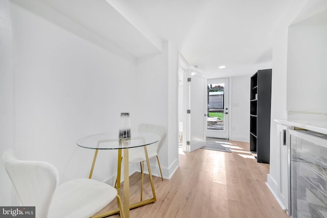 corridor with light wood-type flooring and wine cooler