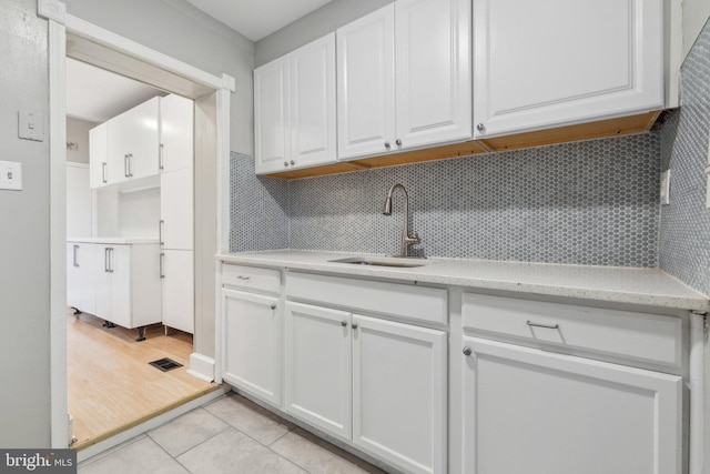 kitchen with decorative backsplash, light hardwood / wood-style floors, white cabinetry, and sink