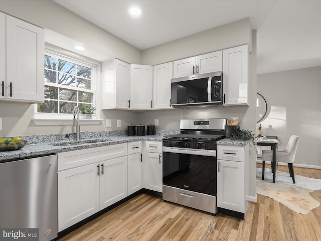 kitchen featuring stainless steel appliances, white cabinetry, and sink