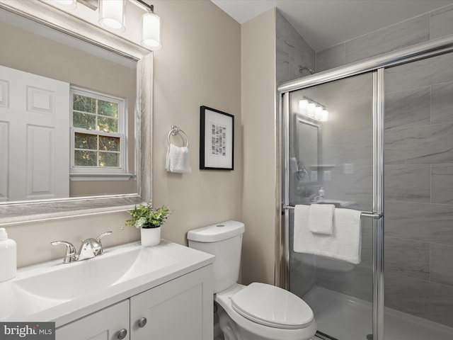 bathroom featuring a shower with door, vanity, and toilet