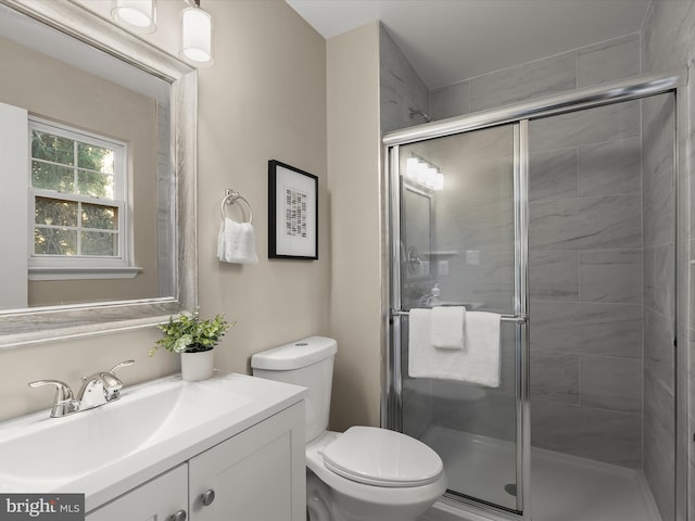 bathroom with vanity, a shower with shower door, and toilet