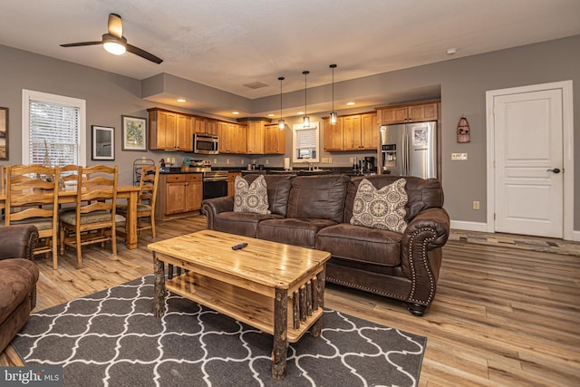 living room with ceiling fan, light hardwood / wood-style floors, and sink