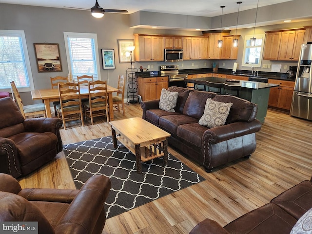 living room with ceiling fan, sink, and light hardwood / wood-style floors